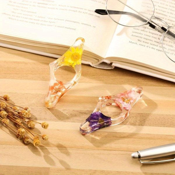 two handmade transparent thumb rings featuring dried flowers, designed as personalized bookmarks for book lovers and teachers, adding a stylish touch to reading.